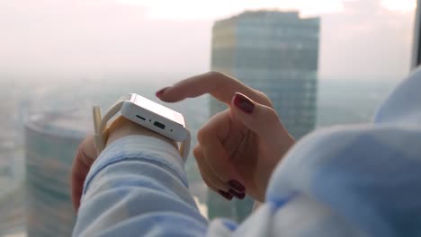 Mano-de-mujer-usando-reloj-inteligente-blanco-ponible-en-la-oficina---vista-lateral-de-cerca