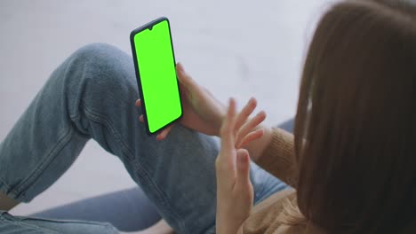 Phone-with-Green-Screen-and-Chroma-Key-Closeup.-Chromakey-Mockup-with-Tracking-Markers-and-Alpha-Matte.-POV-is-Vertical-Template-of-Device-in-Modern-House-Closeup.-Scroll-Up-Online-News-at-Cellphone