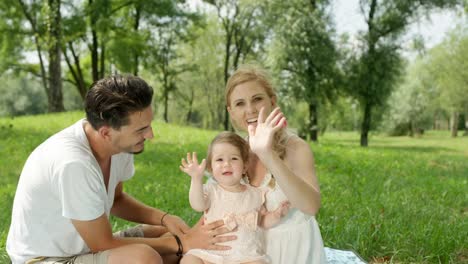 CLOSE-UP:-Cute-parents-with-beautiful-baby-girl-sitting-on-blanket-in-park