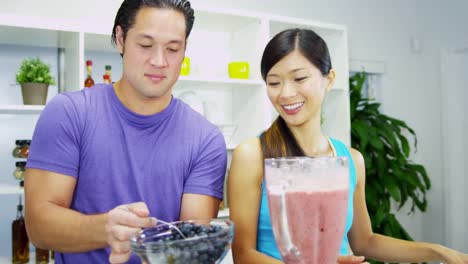 Pareja-joven-étnica-con-jugo-de-fruta-orgánica-de-blender