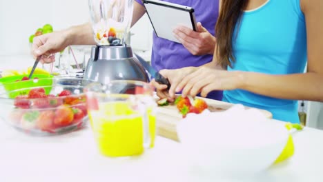 Pareja-joven-étnica-con-jugo-de-fruta-orgánica-de-blender