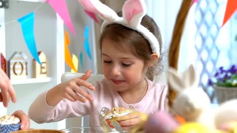 Joven-madre-y-su-hija-con-orejas-de-conejo-cocinar-cupcakes-de-Pascua