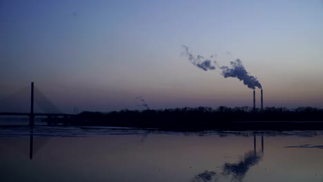 The-smoky-plant-on-the-background-of-the-river-and-the-setting-sun