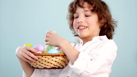 A-child-holds-a-Easter-bunny-and-a-set-of-decorative-Easter-eggs.-The-boy-laughs-cheerfully.-Slow-Motion