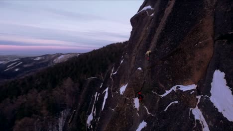 Aerial-view-of-a-rock-climber-climbing-a-steep-cliffs-during-a-sunny-winter-day.