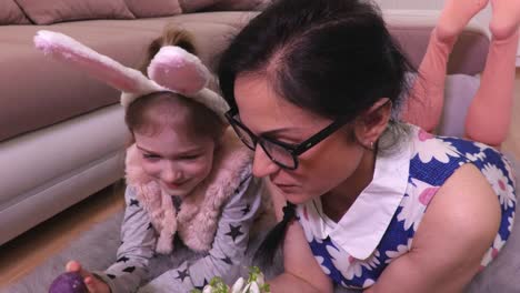 Mother-and-daughter-with-Easter-eggs-and-snowdrops-on-the-floor