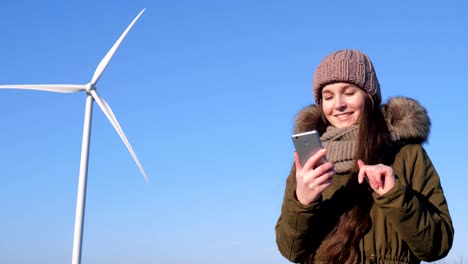 Internet-chatting,-nice-female-sits-in-social-networks-using-mobile-phone-beside-windmill