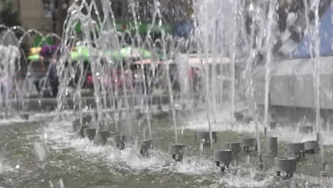 Der-Brunnen-in-der-Stadt-ist-close-up.-Wasserstrahlen-verlangsamt.-Stadtstraße-Sommer