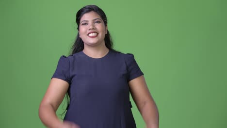 Young-overweight-beautiful-Indian-businesswoman-against-green-background