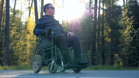 Physically-challenged-man-is-sitting-in-his-powered-wheelchair-next-to-the-forest