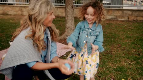 Grandmother-and-granddaughter-playing-with-eggs-during-Easter-egg-hunt