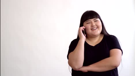 Plus-Size-Mädchen-mit-Telefon-im-Gespräch-auf-weißem-Hintergrund.-Asiatische-Mädchen-Lächeln-auf-den-Lippen-und-am-Telefon-sprechen