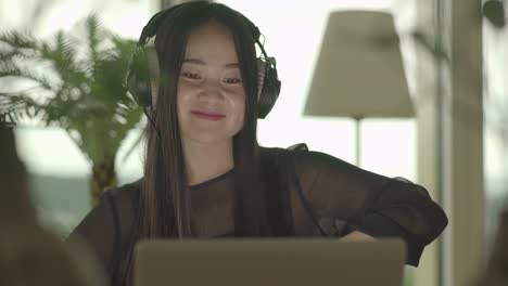 Young-woman-sitting-at-home-working-with-computer-and-chair-dancing