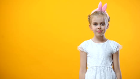 Playful-female-kid-holding-colored-egg-in-front-of-eye,-Easter-symbol,-holiday