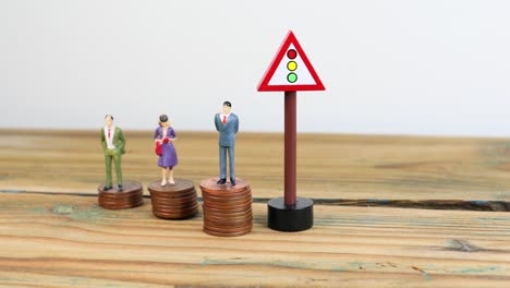 Miniature-people-standing-on-piles-of-coins