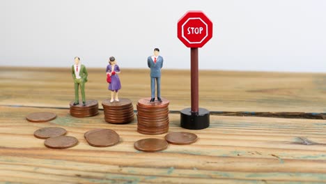 Miniature-people-standing-on-piles-of-coins