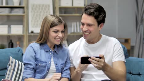 Animando-joven-pareja-excitada-de-éxito-mientras-que-la-observación-en-Smartphone