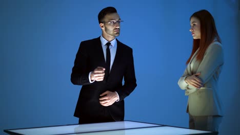 The-business-man-and-a-woman-working-with-a-virtual-display-on-a-blue-background