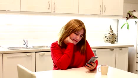 Woman-in-kitchen-using-smarthone