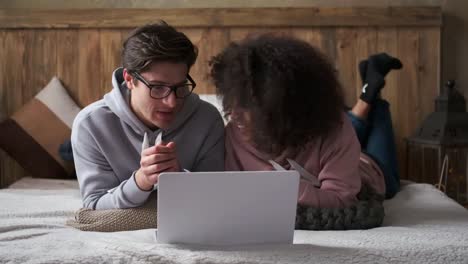 Couple-discussing-and-using-laptop-in-bedroom