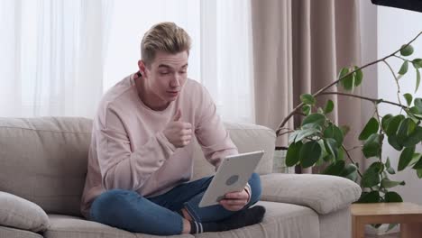 Man-giving-thumbs-up-while-video-conferencing-on-digital-tablet