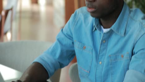 African-american-man-using-laptop-computer-in-cafe-sharing-business-ideas