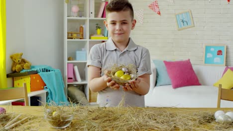 Niedliches-kleines-Knabenpochen-mit-Ostereier-in-Hay-Nest