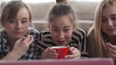 Compañeros-de-cuarto-viendo-contenido-multimedia-en-el-ordenador-portátil-mientras-que-el-café-y-palomitas