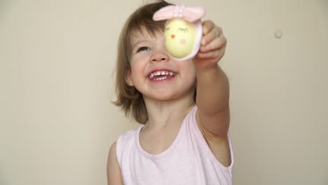 Portrait-of-cute-baby-girl-shows-chicken-egg-in-hands,-decorated-for-Easter-chick.