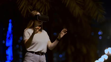 Young-woman-in-virtual-reality-glasses-in-the-night-city-moves-her-hands