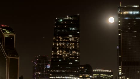 Der-Mond-steigt-über-die-beleuchtete-Autobahn-und-die-Nachtstadt,-Zeitraffer