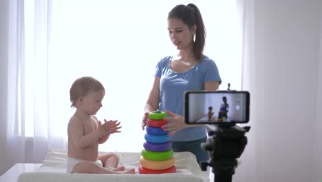 videoblog,-infant-boy-with-woman-played-by-educational-toys-and-recording-social-media-video-in-streaming-live-on-cell-phone-for-subscribers-in-social-networks