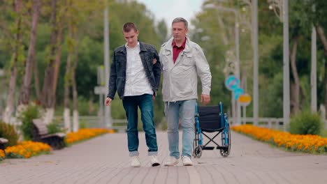 Dad-helps-disabled-son-to-go,-family-support.-Disabled-guy-walking-down-the-road.