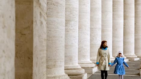 Frau-mit-ihrer-Tochter,-die-zwischen-den-Säulen-auf-der-Piazza-San-Pietro,-Vatikan,-spazieren-geht