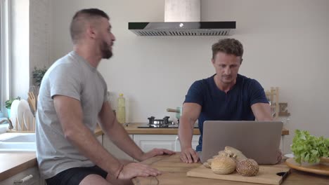 Gay-male-couple-arguing-impatiently-while-using-notebook-computer-at-table