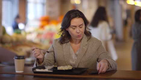 Frau-mit-Smartphone-beim-Mittagessen-auf-dem-Lebensmittelmarkt