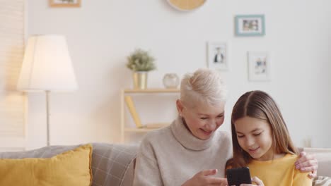 Abuela-caucásica-enseñar-chica-cómo-utilizar-el-teléfono-inteligente