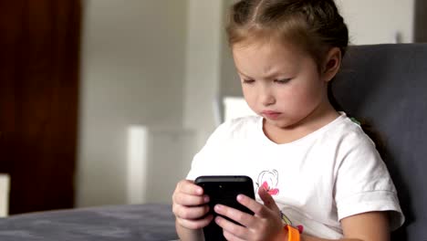 Niño-casual-sentado-en-un-sofá-en-casa,-jugando-y-tocando-un-teléfono-móvil