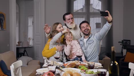 Nahaufnahme-von-freudigen-angenehmen-Familie,-die-um-den-Esstisch-sitzen-und-Selfie-machen