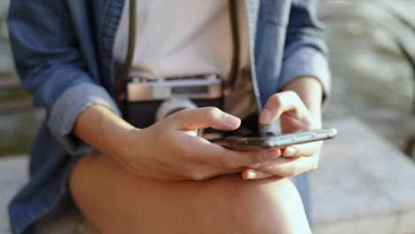 Close-up-hand-scrolling-feed-on-smartphone-social-media-communication-while-sitting-on-a-chair-beside-Chao-Phraya-river-in-Thailand-at-the-beautiful-sunset.