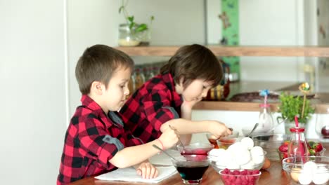 Two-children,-boys,-coloring-easter-eggs-at-home,-eating-strawberries