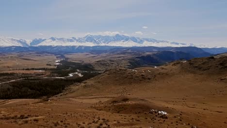 Un-vuelo-sobre-un-hermoso-valle-con-montañas-nevadas-en-la-distancia