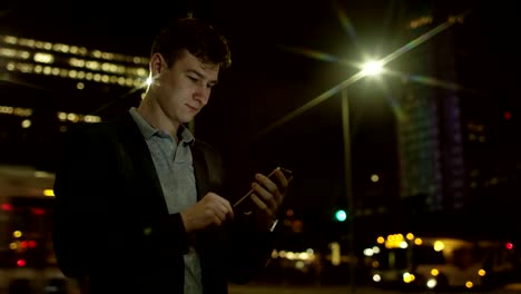 Young-handsome-man-is-using-his-smartphone-for-social-network-on-a-street