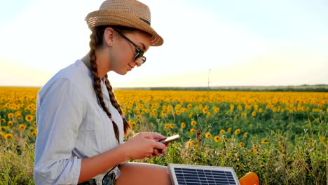 girl-communicates-in-social-network-using-mobile-and-solar-panel-on-background-field,-young-woman-browsing-cellular-phone