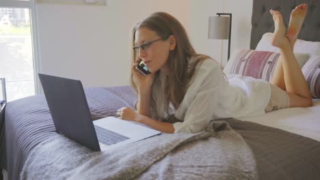 Kaukasische-Frau-Haus-urban-arbeiten-Online-Laptop-Schlafzimmer-Bett