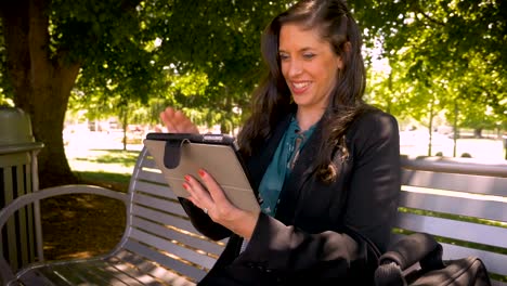 Happy-smiling-woman-in-her-30s-holding-touchpad-digital-tablet-outside