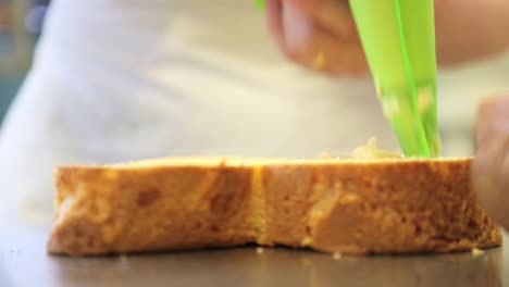 pastry-chef-hands-stuffed-Easter-sweet-bread-cake-with-custard,-closeup-on-the-worktop-in-confectionery