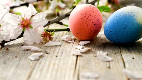 Huevos-de-Pascua-panorámica,-antigua-mesa-de-madera-y-pétalos-de-flor-de-almendra