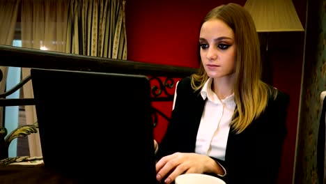 Young-business-woman-typing-on-laptop-text-sitting-in-the-restaurant