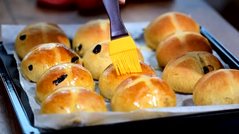 Hausgemachte-Ostern-traditionelle-Hot-Cross-Buns.-Weibliche-Hände-mit-Sirup-bedecken.